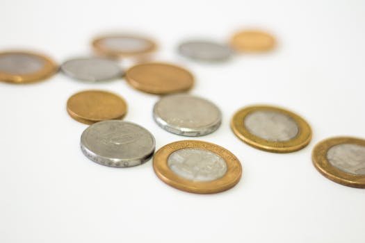 Collection of assorted gold and silver coins scattered on a white surface, offering a modern financial concept. orçamento