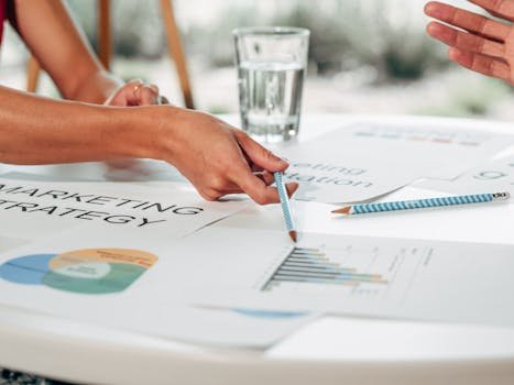 Hands discussing marketing strategy with charts in an office setting. afiliado