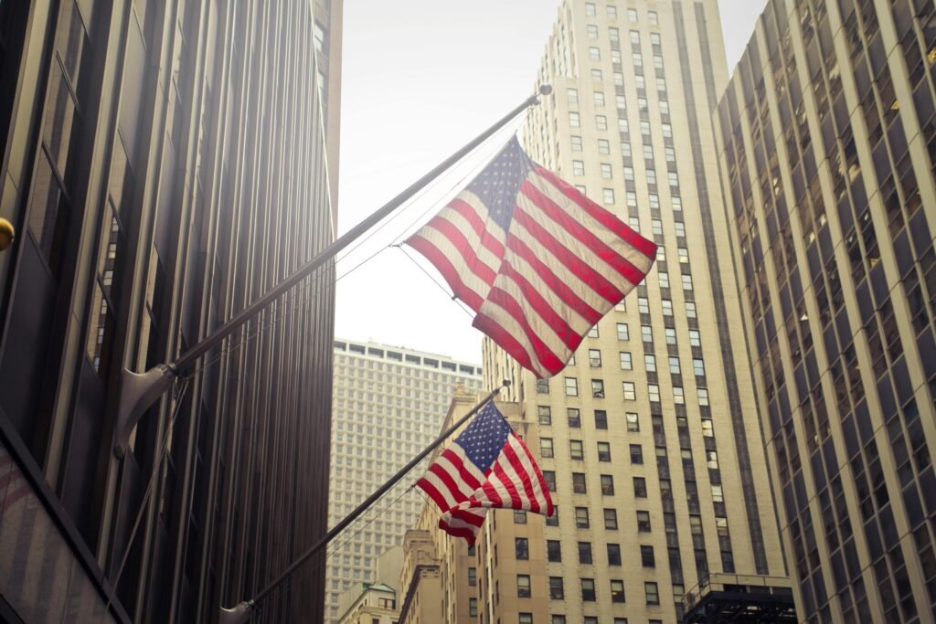 American flags waving among New York skyscrapers, showcasing urban patriotism.